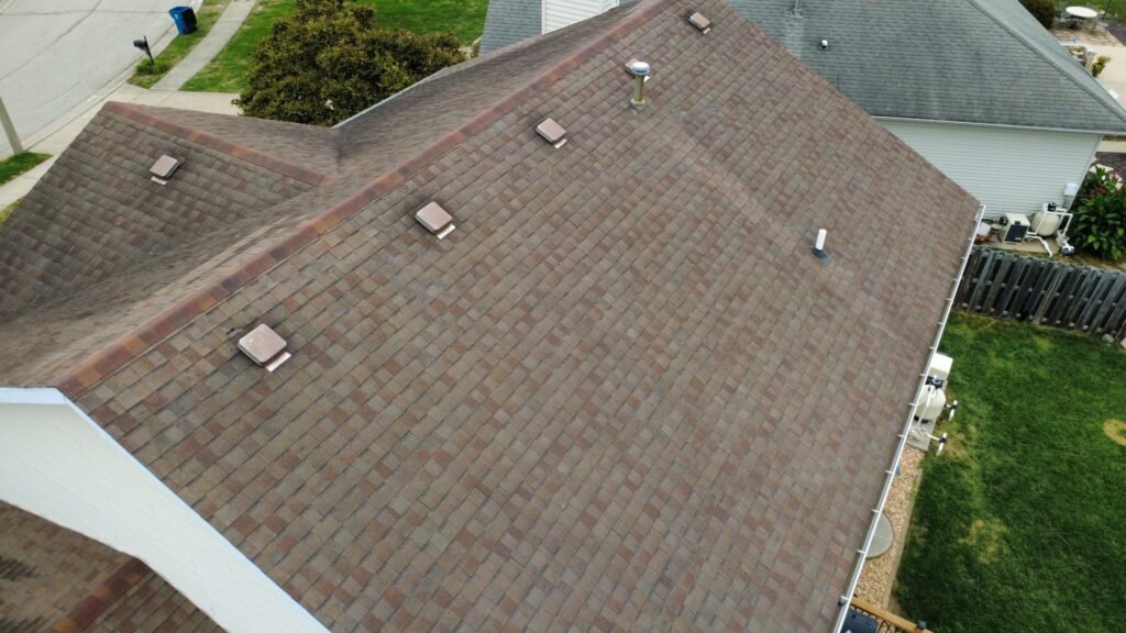 Close-up of faded, worn brown shingles and roof vents before replacement on a Springfield, IL home