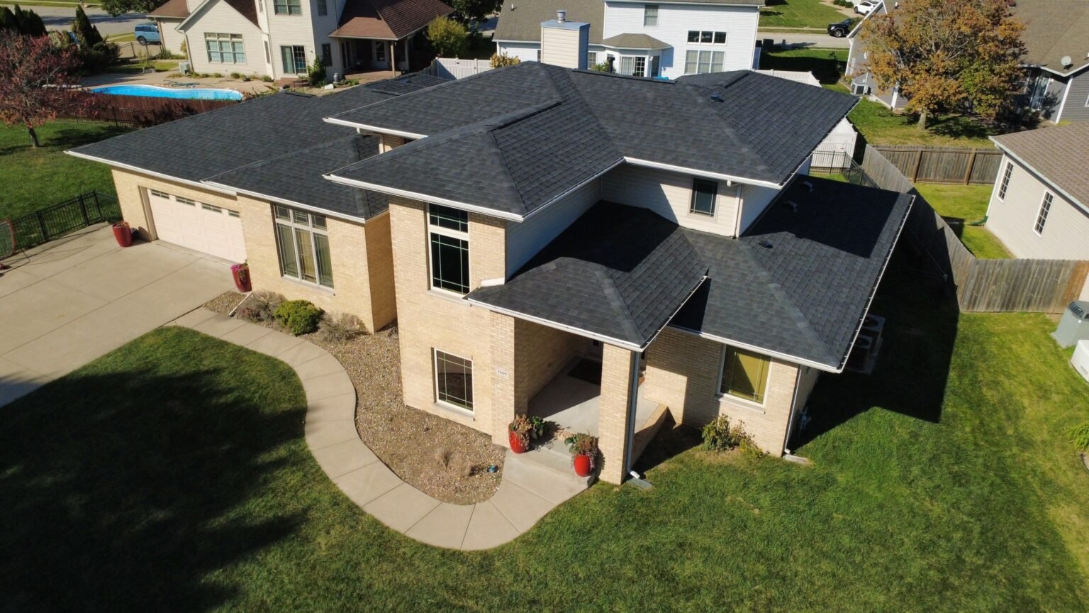 Aerial view of a two-story tan brick Springfield, IL home with a new dark IKO Dynasty Blackstone shingle roof installed by Westside Construction
