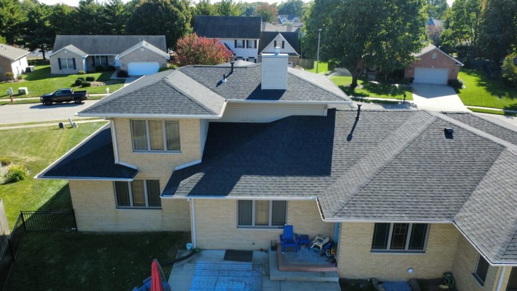 Back of a Springfield, IL brick home showing the completed IKO Dynasty Blackstone roof replacement and chimney
