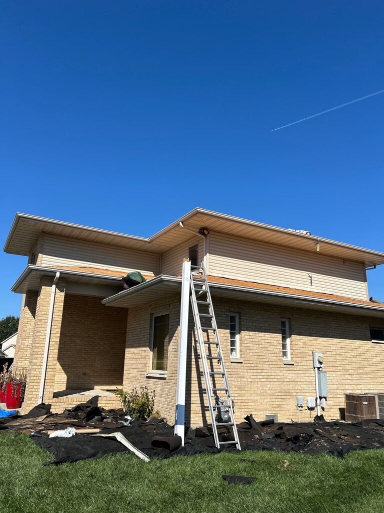 Roofing ladder and tarps covering landscaping at the corner of a Springfield, IL home during roof replacement prep