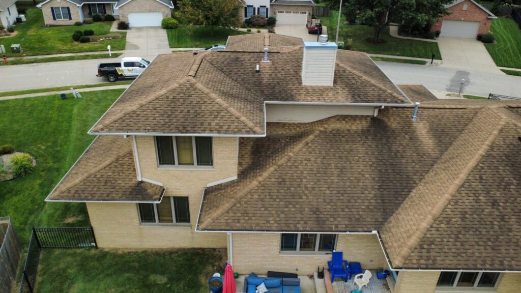 Back of a Springfield, IL brick home showing worn brown shingles and chimney before roof replacement