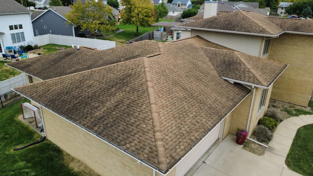 Aerial side view of an aging brown asphalt shingle hip roof on a Springfield, IL home before replacement